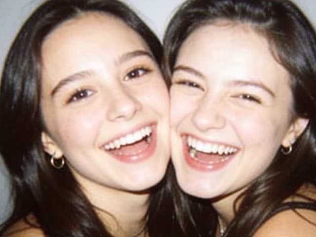 The same two friends, heads tipped together, still laughing